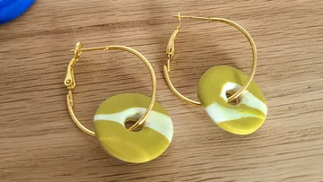 Goldene Creolen auf Holzoberfläche.