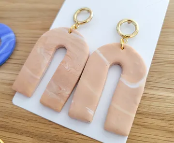 Beige earrings on wooden surface.