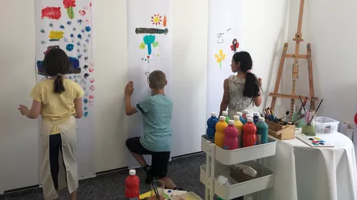 Kinder malen auf großen vertikalen Papieren drinnen.