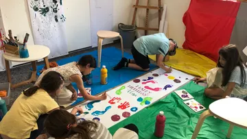Kinder malen drinnen ein Geburtstagsbanner.