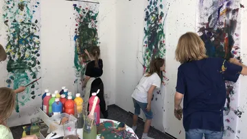 Children painting on walls indoors.