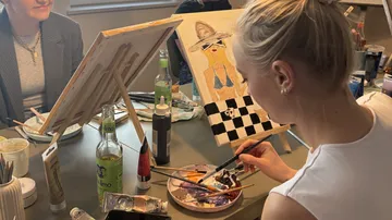 Woman painting in art class setting.