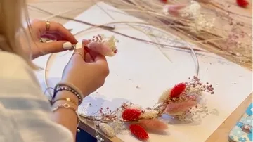 Hands making dried flower wreath indoors.