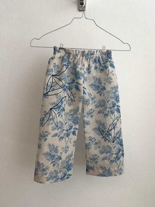 Pants with floral pattern hanging on hanger.