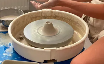 Pottery wheel with hands shaping clay.