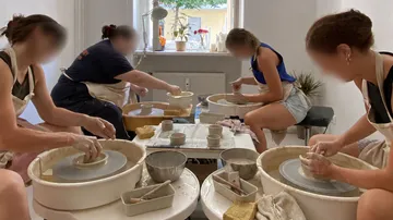 People crafting pottery on wheels indoors.