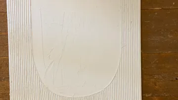 Textured white artwork with wood background.