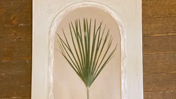 Palm leaf displayed on textured panel.