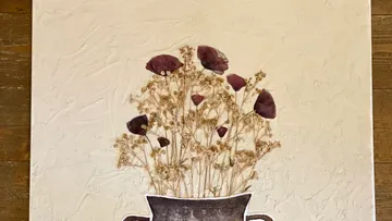Getrocknete Blumen in Vase auf Texturhintergrund.