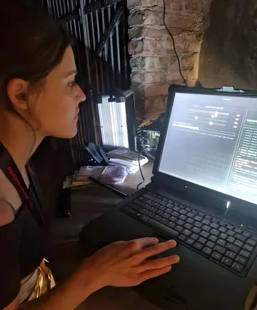 Person using laptop in dimly lit room.