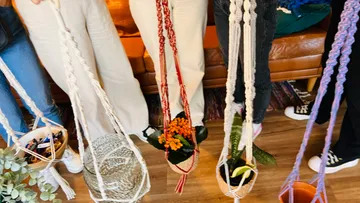 People holding hanging macramé planters indoors.
