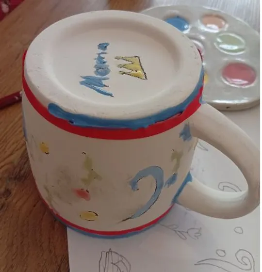 Painted ceramic mug on wooden table.