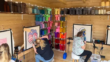 Frauen fertigen Teppiche in einem Garn-gefüllten Atelier.