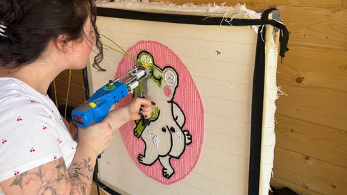 Person benutzt Tufting-Pistole auf Leinwand.
