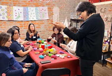 Frauen stricken um einen Tisch in einem Kurs.