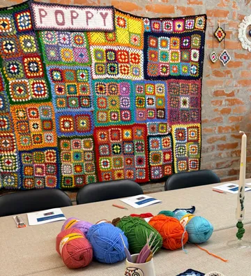 Crochet squares displayed on brick wall.