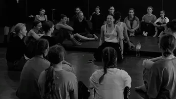Gruppe sitzt und diskutiert im Tanzstudio.