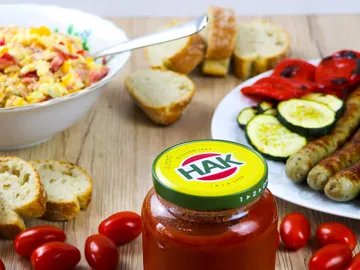 Glas mit Sauce, umgeben von Brot und Gemüse.