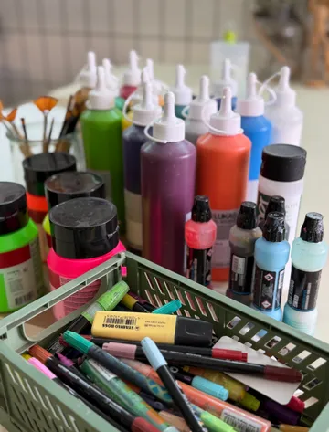 Paint bottles and markers on a tabletop.