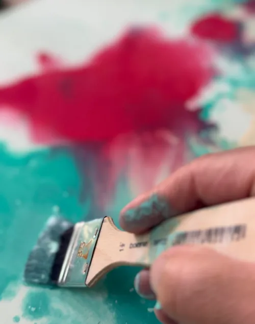 Hand holding brush painting colorful canvas.