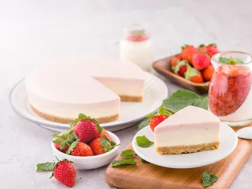 Käsekuchen mit Erdbeeren, auf einem Holzbrett serviert.