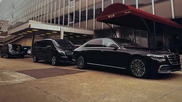 Luxury cars parked outside VIP entrance.