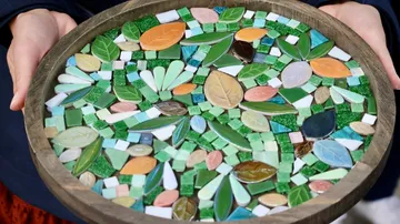 Hände halten buntes Blattmosaik-Kunstwerk.