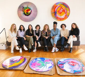Frauen sitzen, bunte Kunst an Wänden.
