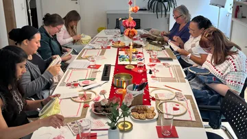 People embroidering together around a decorated table.