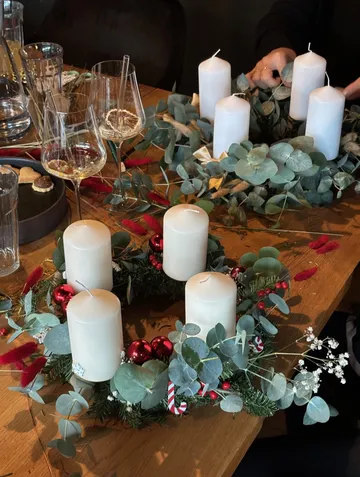 Zwei Adventskränze mit Kerzen auf Tisch.