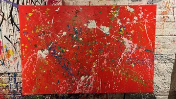 Abstract red canvas with colorful paint splatters.