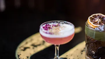 Pink cocktail glass, garnished with flowers.