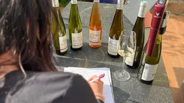 Person probiert Wein an einem Tisch.