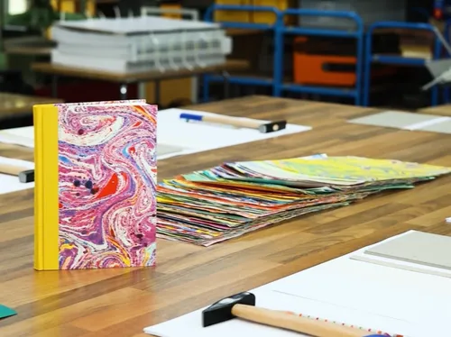 Colorful book on workshop table, surrounded by papers.