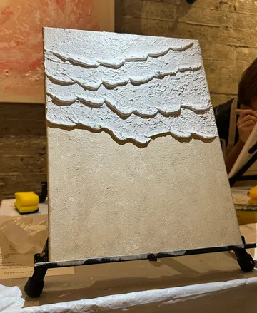 Textured canvas displayed on easel indoors.