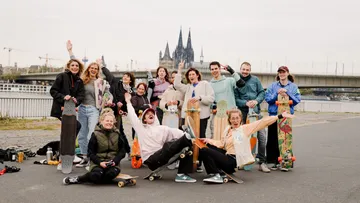 Gruppe posiert mit Skateboards am Fluss