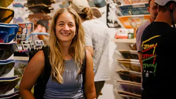 Woman smiling indoors at skateboard shop.
