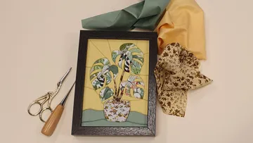 Stoffkunst im Rahmen, Scheren daneben.
