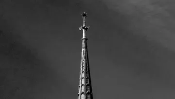 Gotischer Kirchturm vor bewölktem Himmel