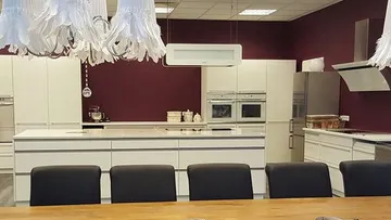 Moderne Küche mit weißen Schränken und Geräten.