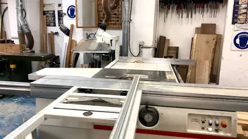Sawing machine operating in a workshop environment.