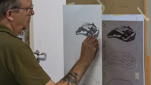 Man sketching on paper in art studio.
