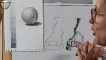 Artist discussing pencil sketches on board.