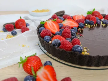 Chocolate cake with fresh berries and a decorative edge.