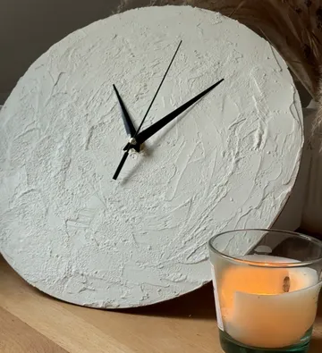 Textured clock shows time near burning candle