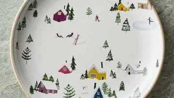 Teller mit Winterdorf und Skifahrer-Illustration.