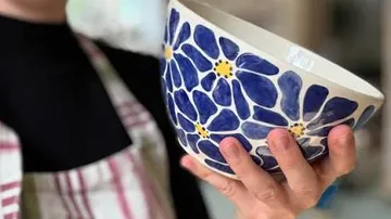 Hand hält blaugeblümte Schüssel.