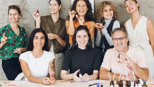 Group holding essential oil bottles, smiling indoors.