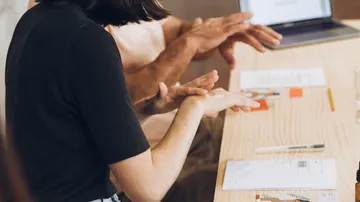 People using sign language in meeting.