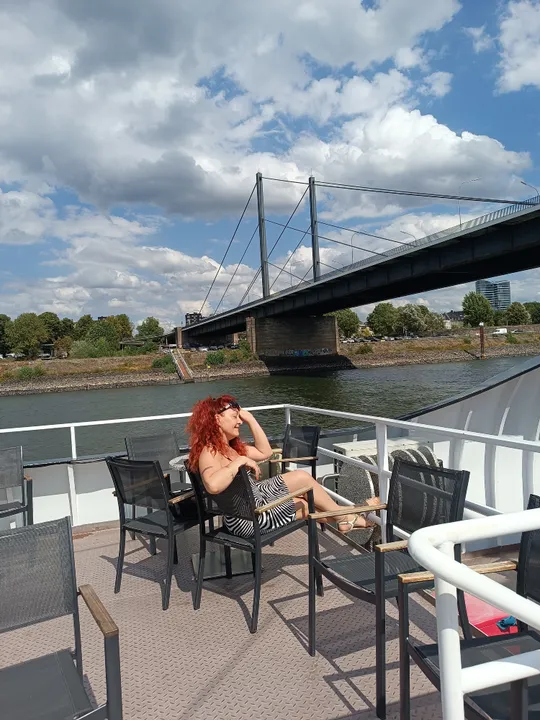Frau entspannt auf Boot, Brücke im Hintergrund.